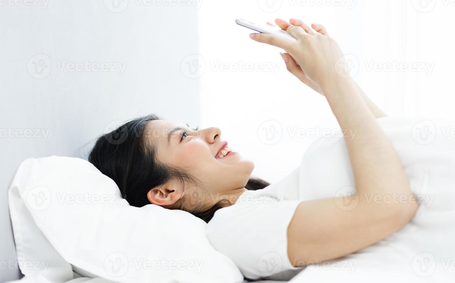image of girl using phone in bed, in the morning photo