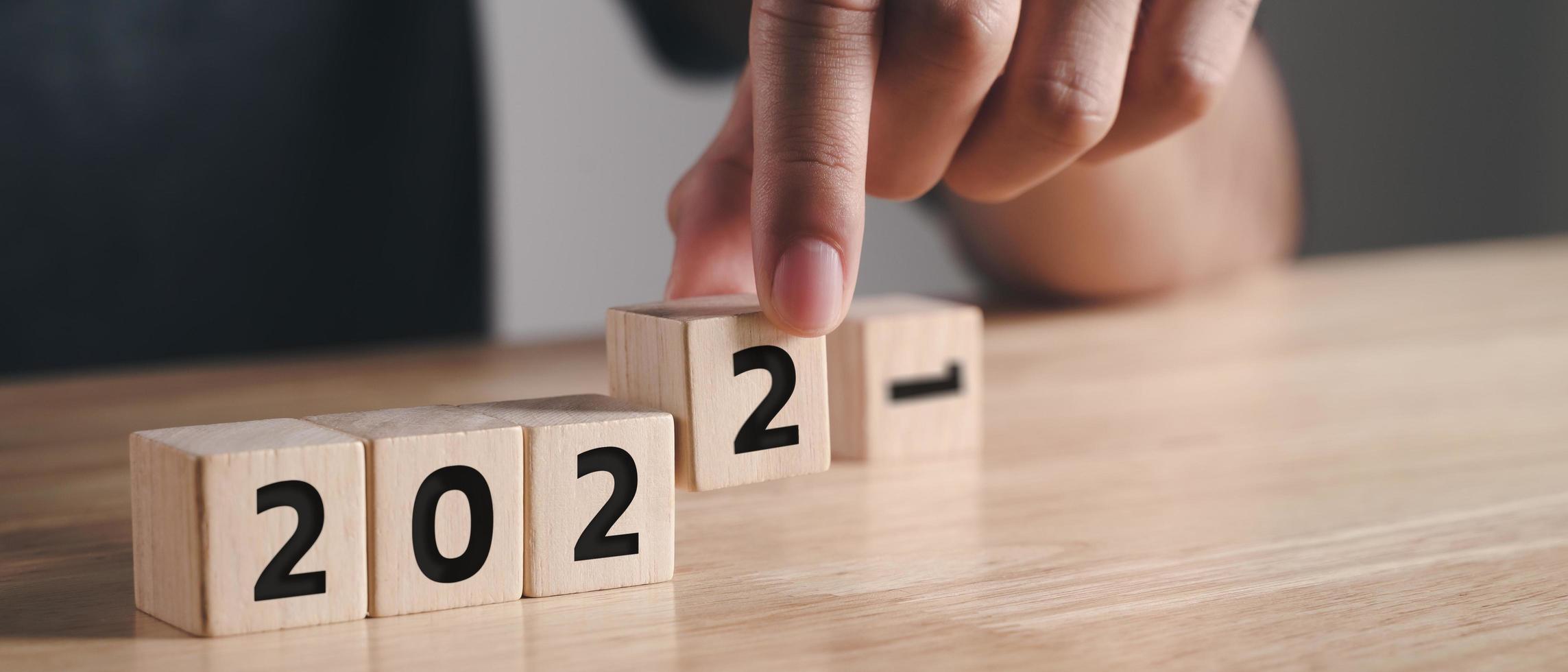 Man hand putting wooden cube block to change 2021 year to 2022 year on wood table with copy space. start to year 2022. happy new years concept. photo