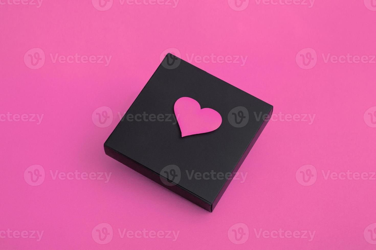 Gift black box with hearts on a pink background. Closeup copy space photo