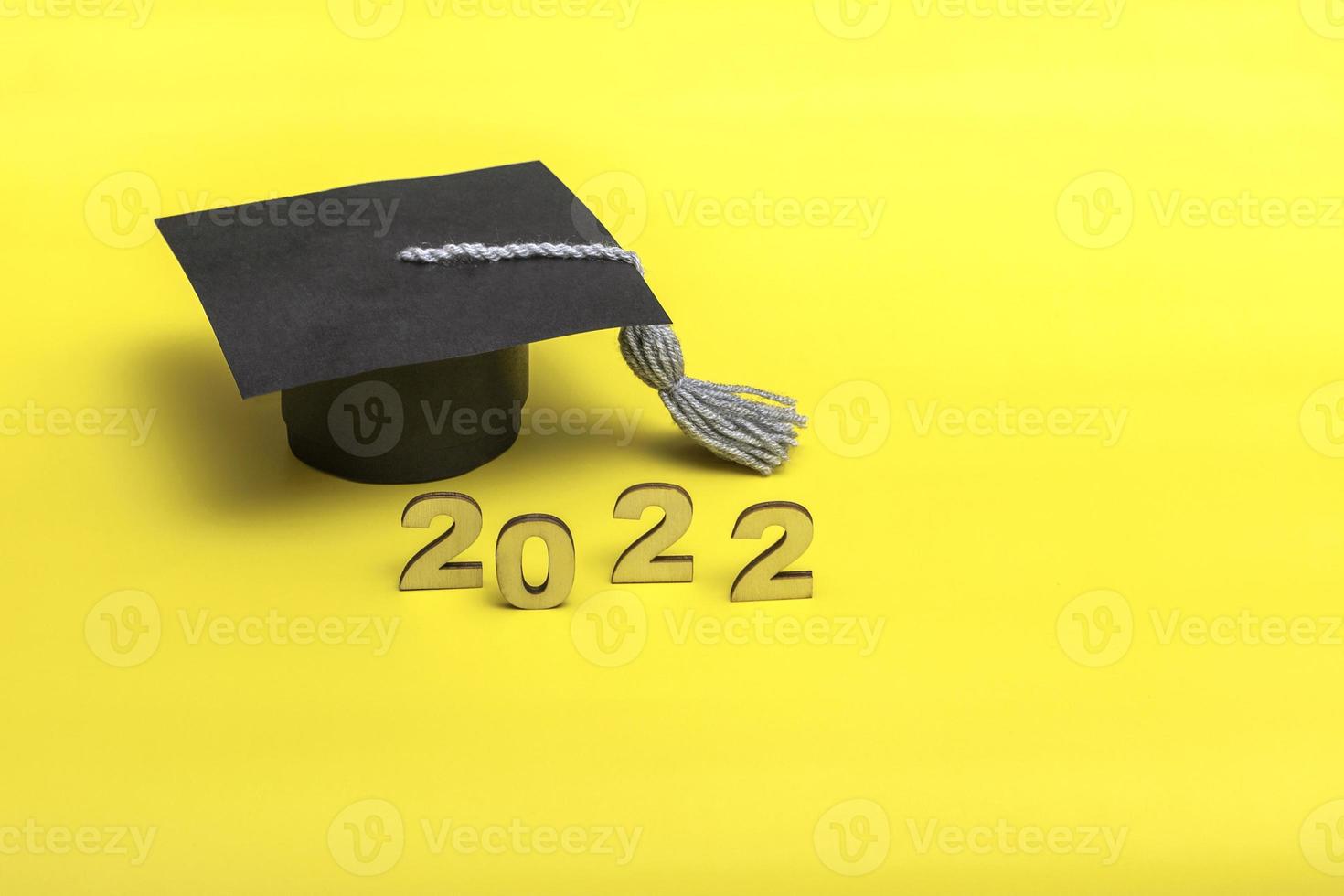 caja de regalo en forma de gorro de graduación. 2022 concepto de lanzamiento sobre fondo amarillo espacio de copia foto