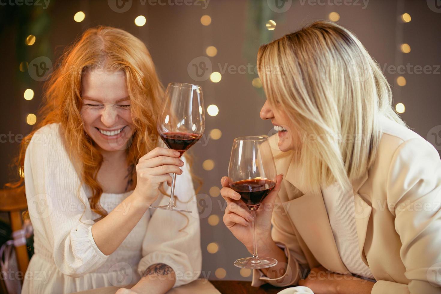 pareja de lesbianas cenando en un restaurante. las chicas beben vino y hablan foto