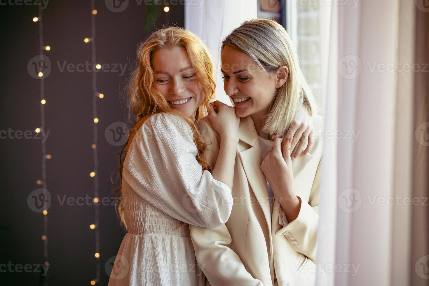 lesbian couple having dinner in a restaurant. One girl hugs her beloved whispering in her ear photo