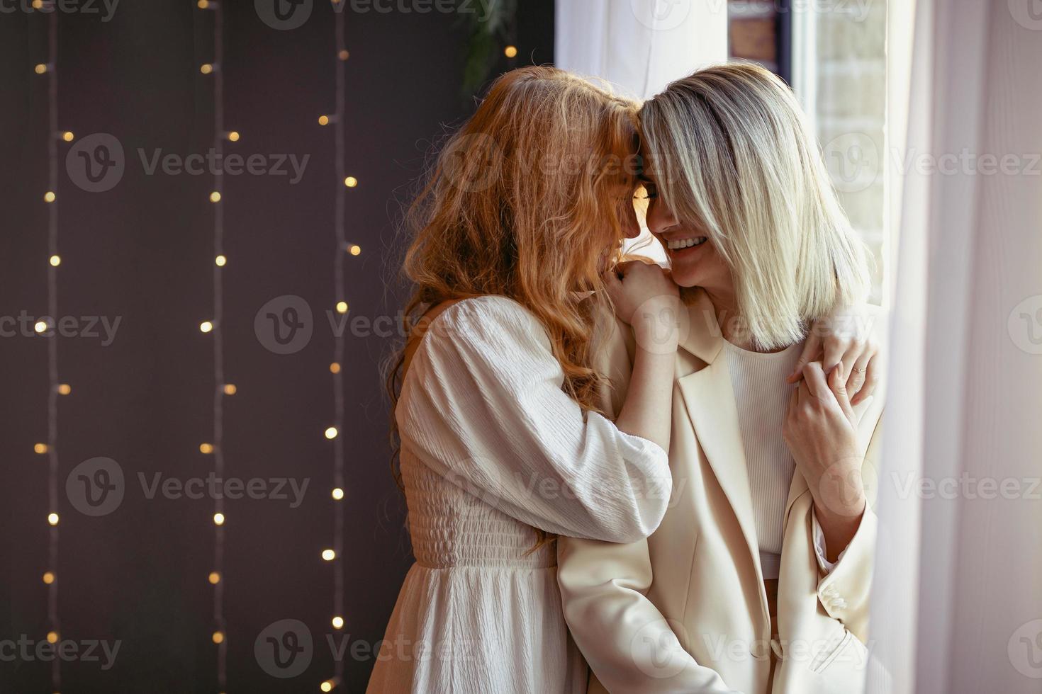 pareja de lesbianas cenando en un restaurante. una niña abraza a su amado susurrándole al oído foto