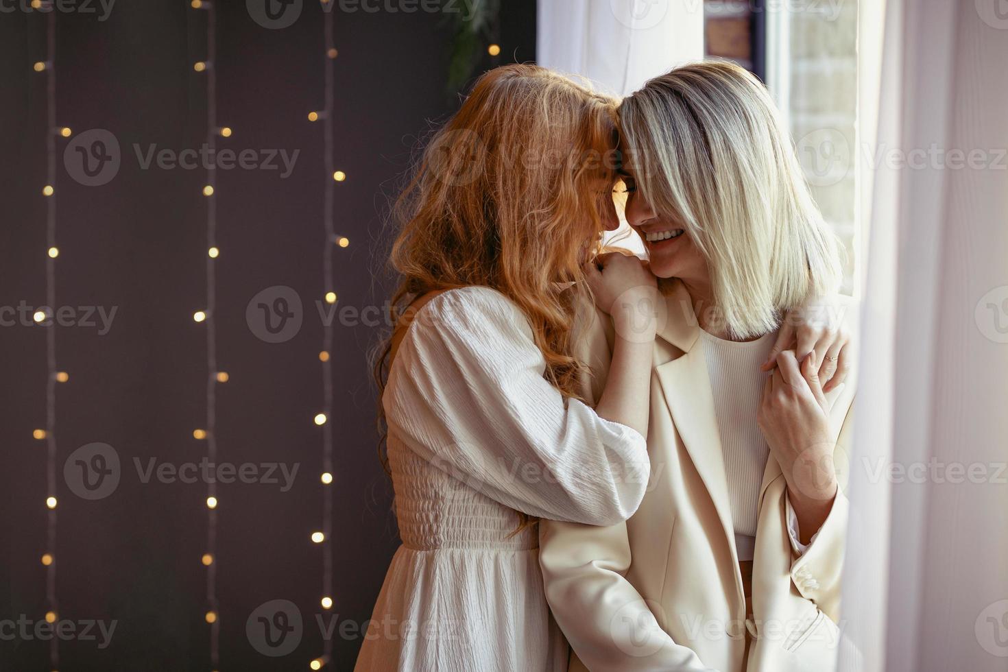 lesbian couple having dinner in a restaurant. One girl hugs her beloved whispering in her ear photo