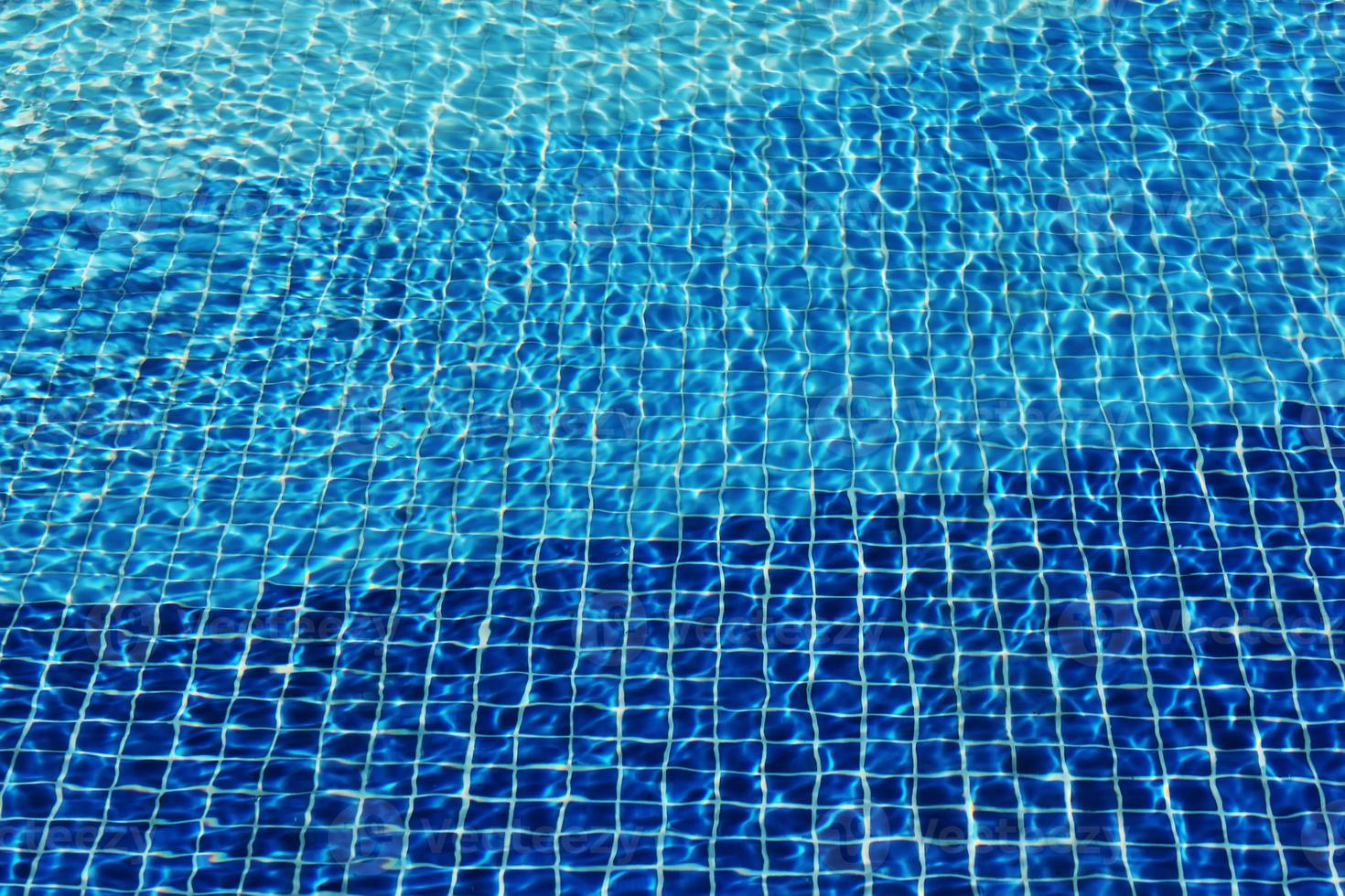 Los cáusticos del fondo del mosaico de la piscina se ondulan como el agua del mar. fluir con olas, deporte y concepto de relajación. fondo de verano. textura de la superficie del agua. vista superior. ondas de agua con foto