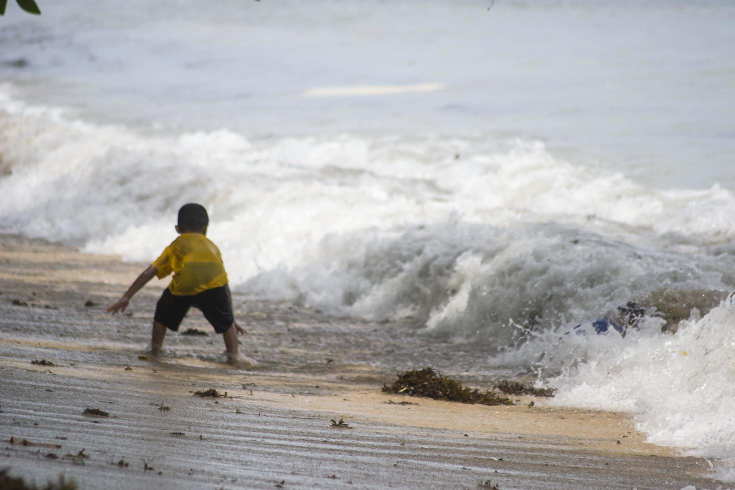 Sorong, West Papua, Indonesia, December 12th 2021. Boys playing against the waves on the beach photo