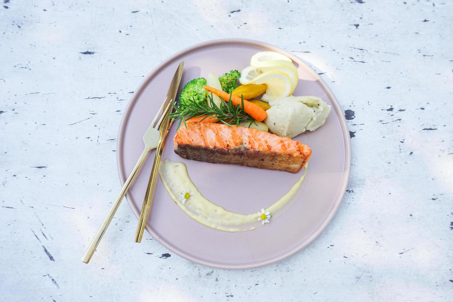 Steak salmon with vegetable broccoli carrot rosemary and lemon on plate seafood - Roasted or grilled salmon steak fish on dining table food outdoor photo