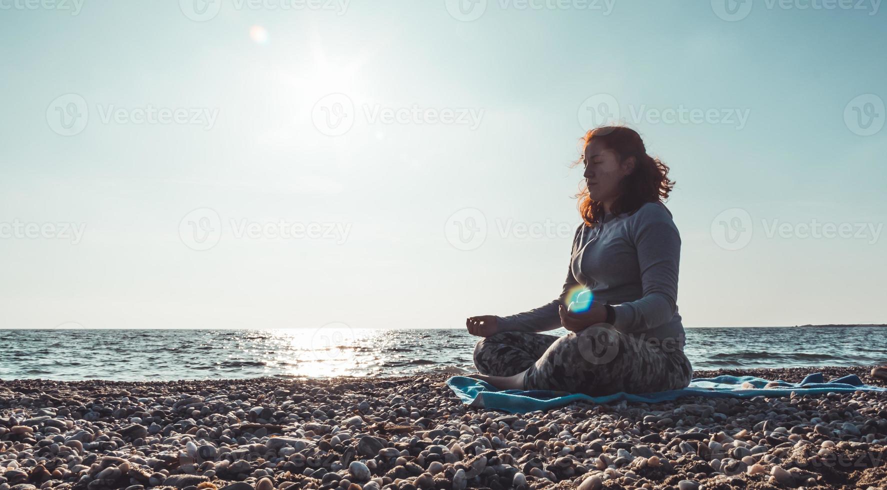 girl meditating on the beach photo