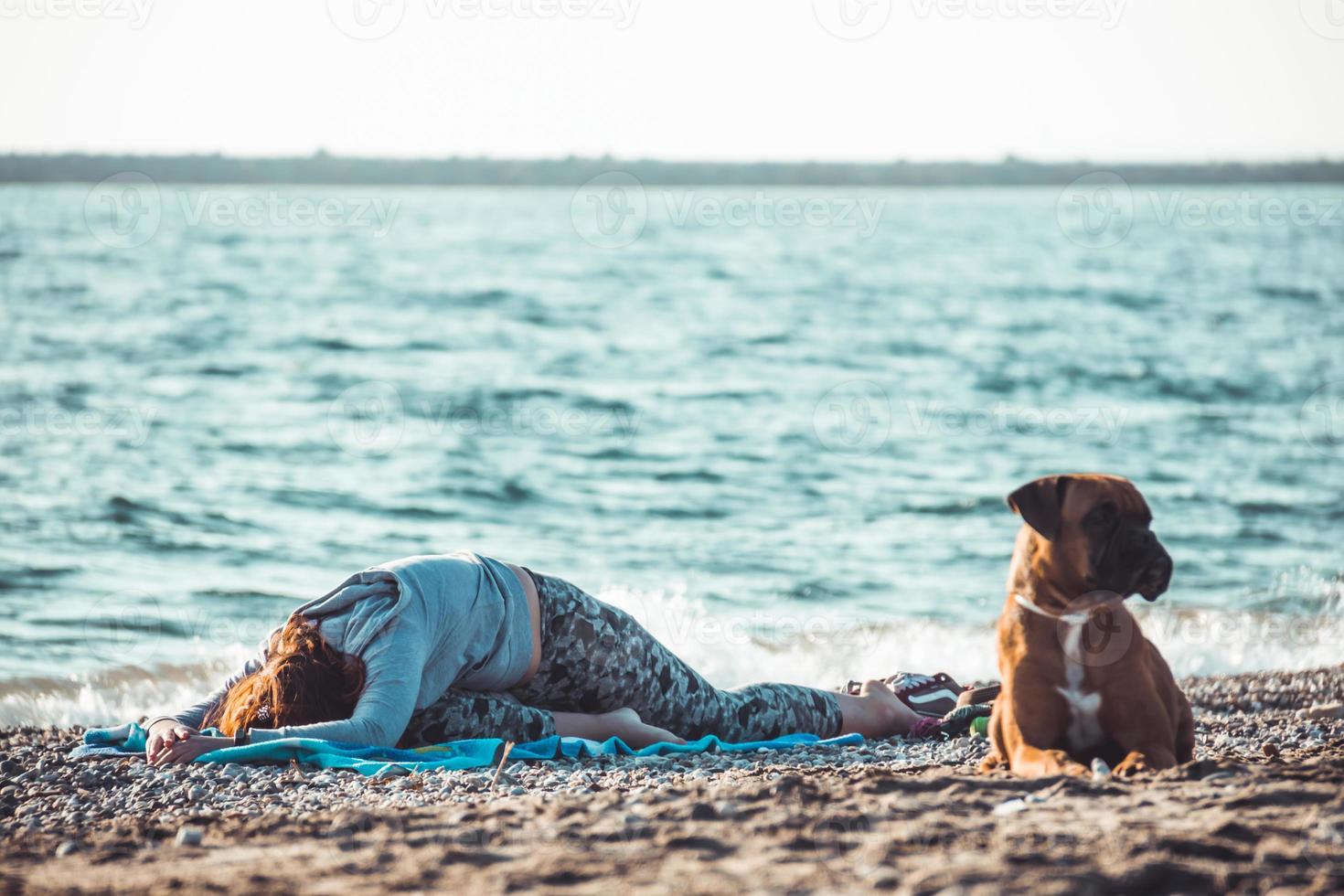 chica haciendo yoga y estiramiento en la playa con su perro foto