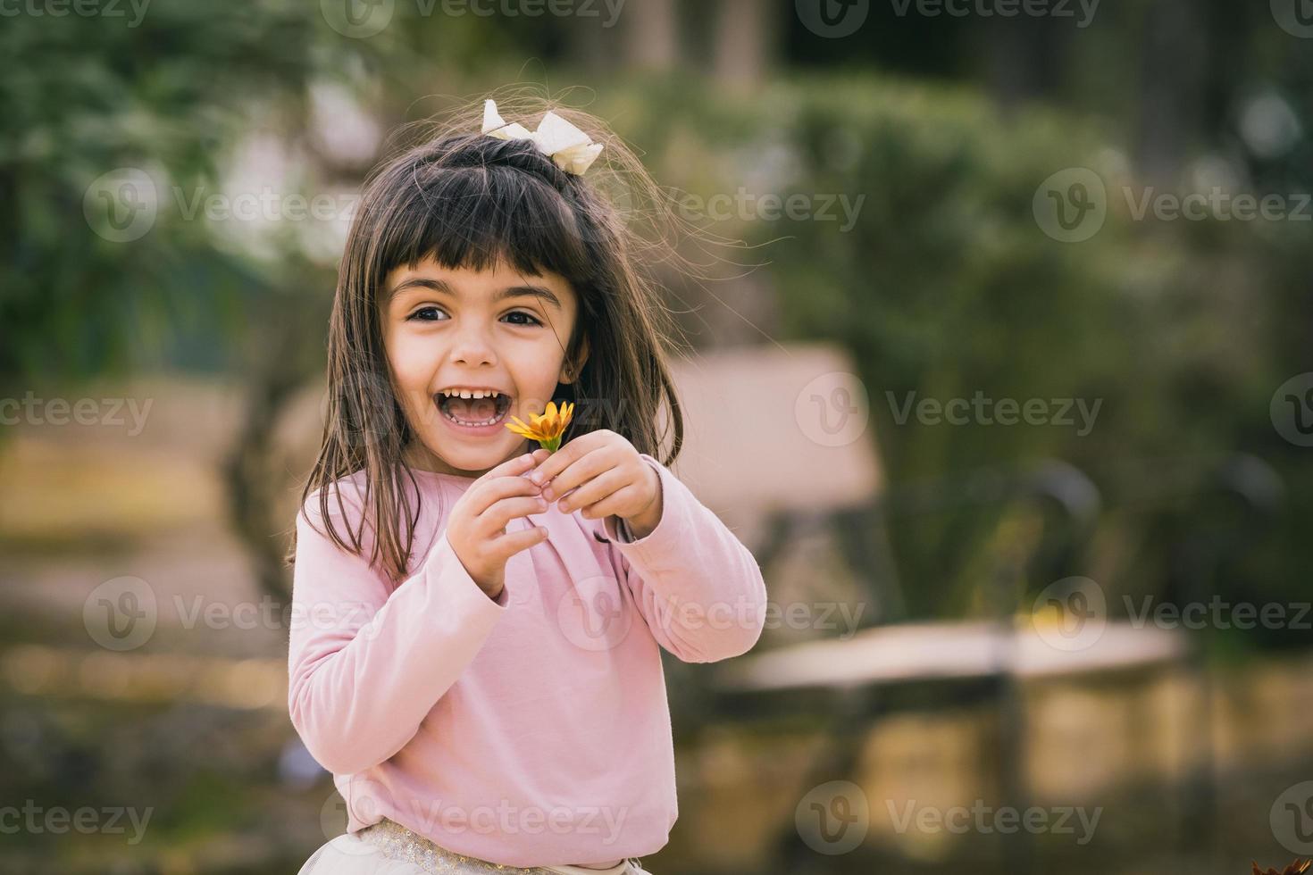 niña cogiendo una flor en un parque. sonriente y feliz con una flor. copia espacio foto