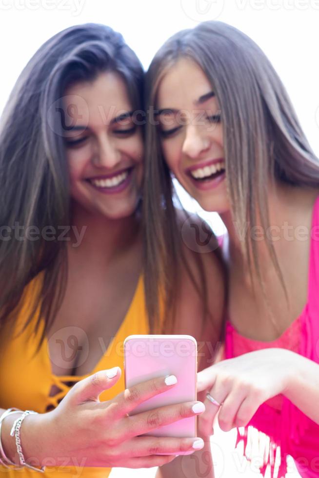 two girls in swimsuits using their cell phones and having fun at the pool. Close up photo