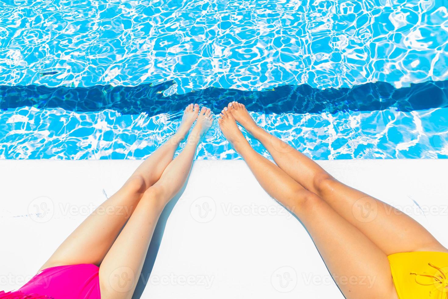 Concepts summer, relaxation, waxing, holidays. Legs of two girls sitting by the pool photo