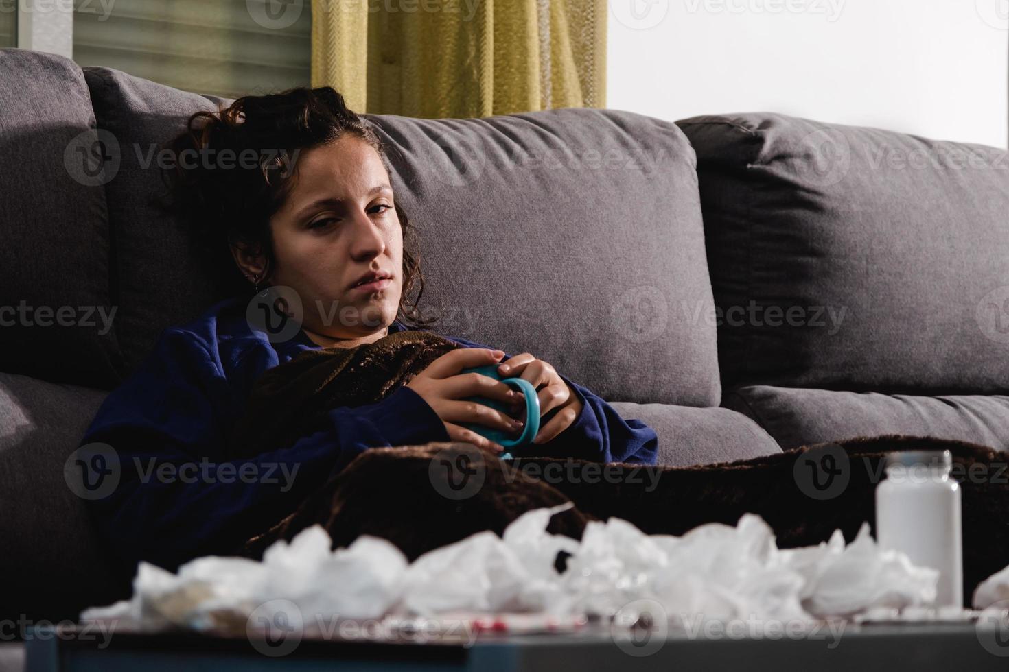 sick woman on the couch at home having a hot drink photo