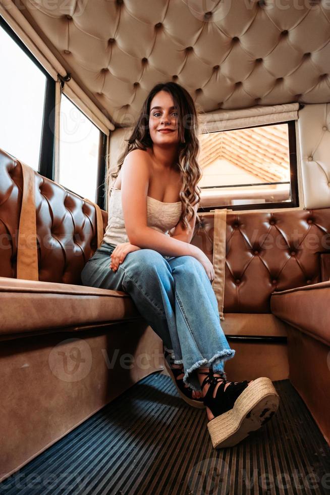 A vertical shot of a caucasian girl sitting inside a compartment with leather seats photo