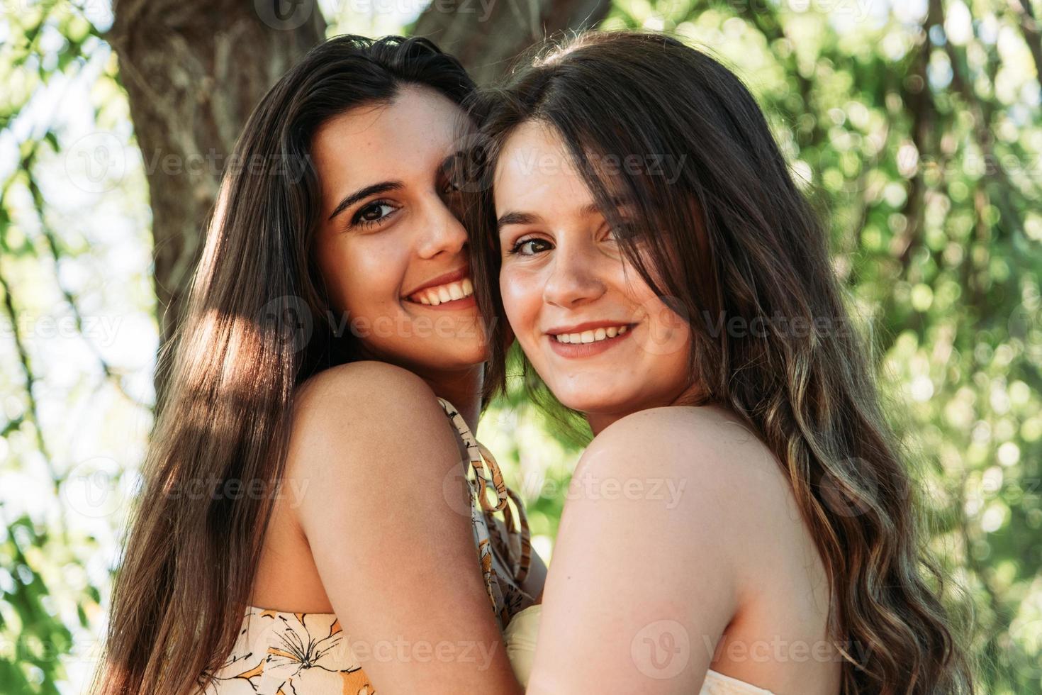 two young women friends in the forest with trees in the background photo