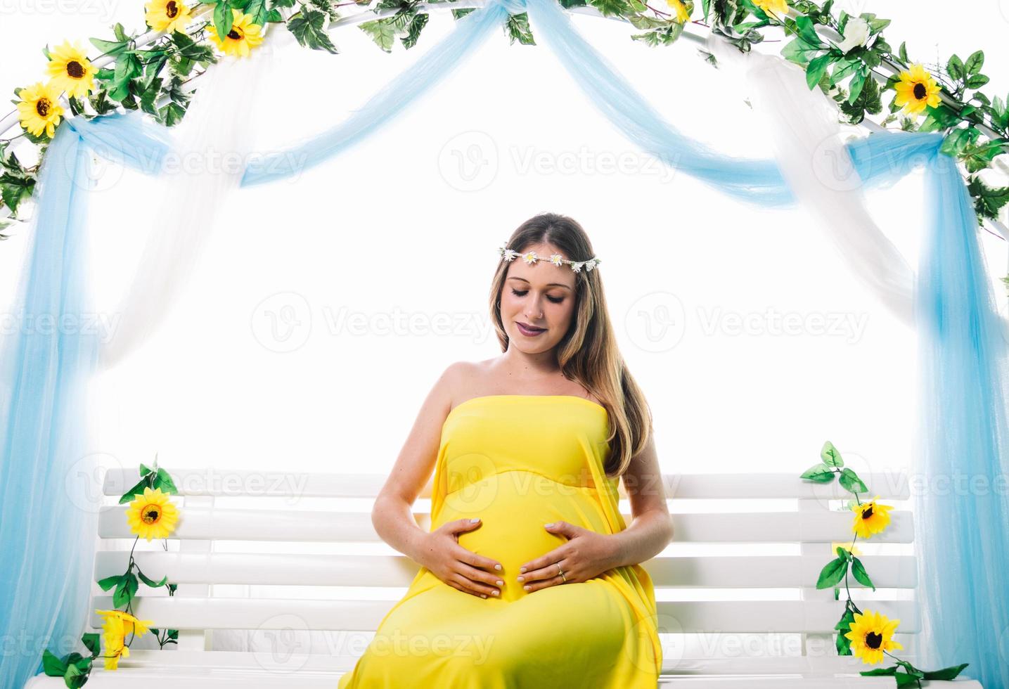 Young beautiful pregnant woman is posing. Looking her belly photo