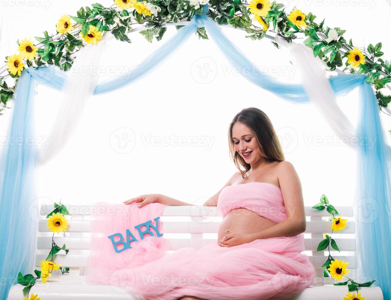 Young beautiful pregnant woman is posing. Looking her belly photo