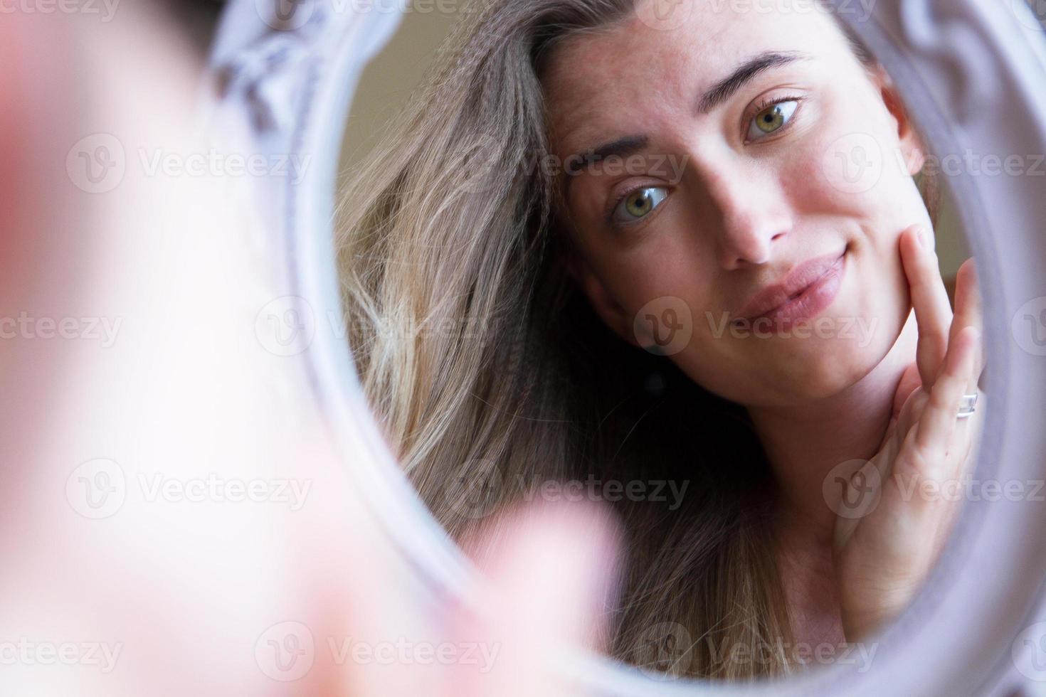 Woman look at the mirror portrait, cute girl touching face an look at the mirror, fashion skin care concept photo