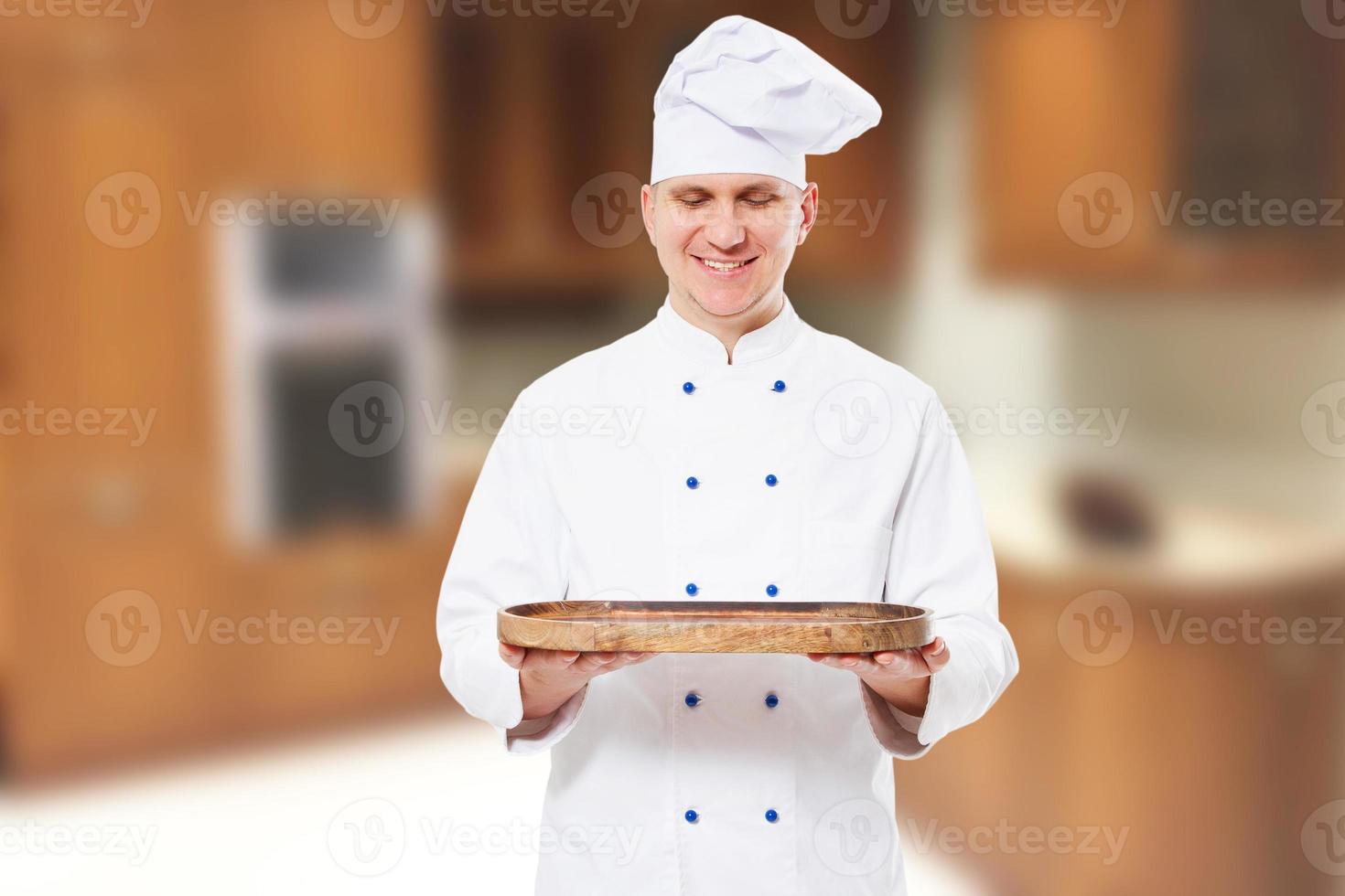 Smile male chef standing in kitchen and hold wooden board mock up with food meal photo