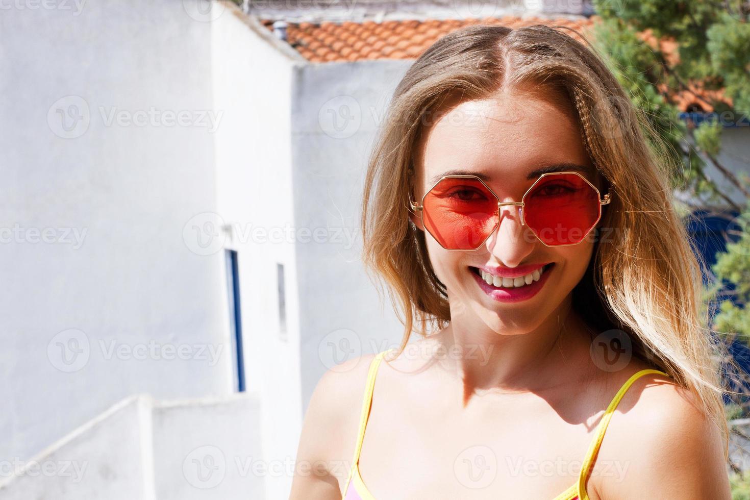 Close up Stunning happy young woman smiling cheerfully at her hotel. Charming woman enjoying summer vacation at luxury resort. Service, travel concept photo