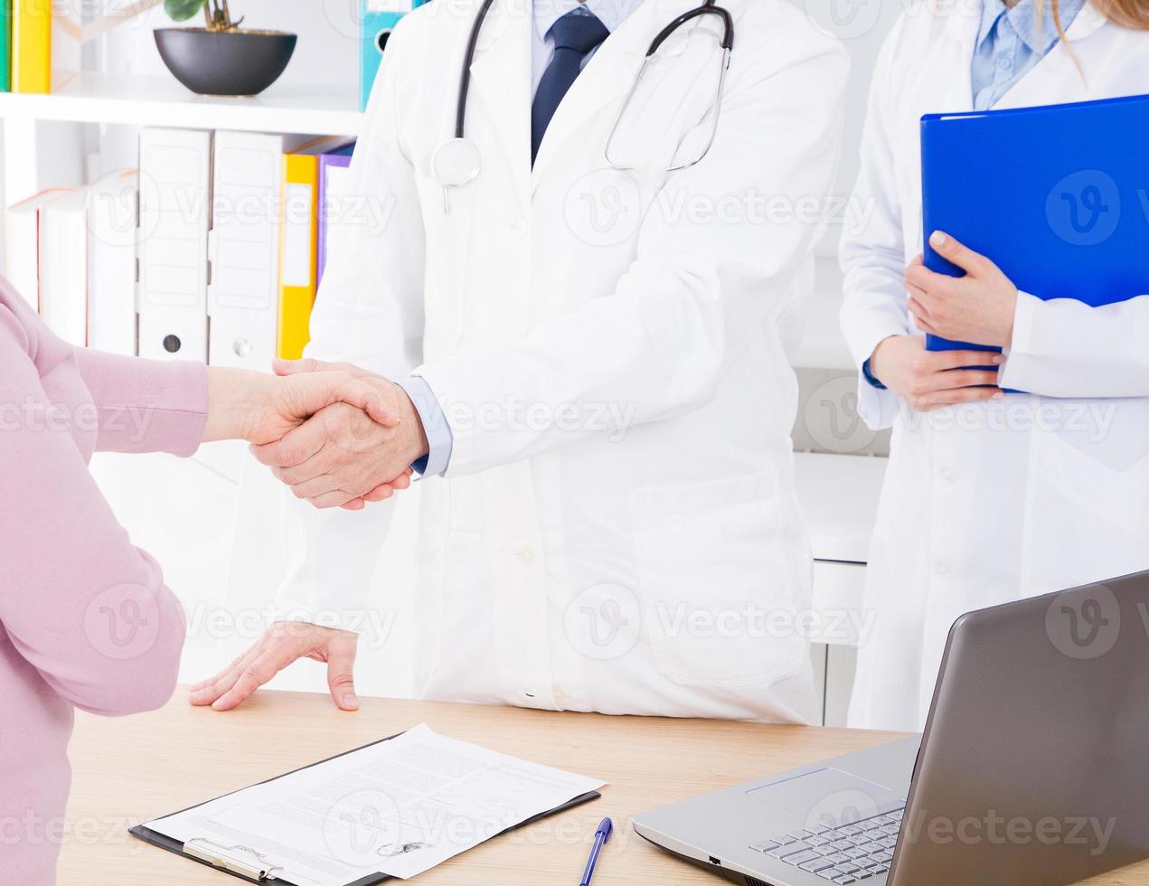 male hand of the doctor shakes the female arm of his patient in clinic, medical office. Healthcare concept, health insurance photo