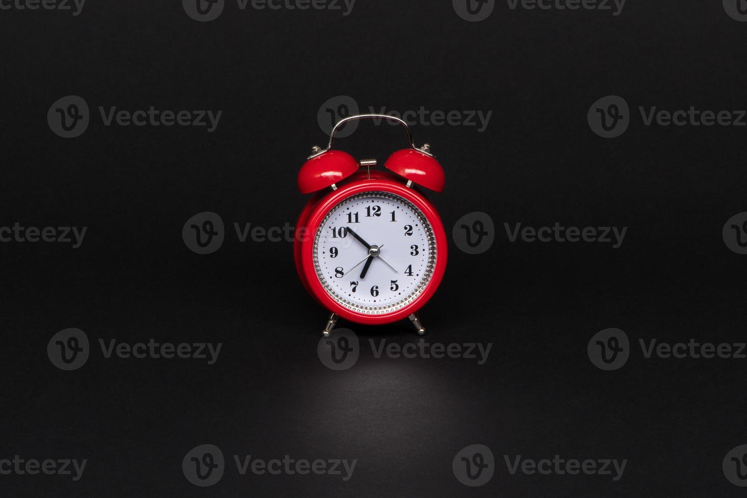 red alarm clock on black background, isolated photo
