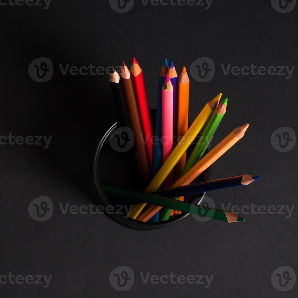 set of colored pencils in a basket on a black background, isolated. back to school photo