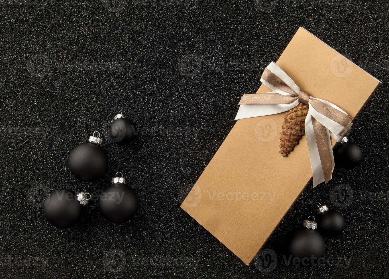 folleto de regalo con adornos para árboles de Navidad sobre un fondo negro granulado. volante con cinta sobre fondo negro granulado foto