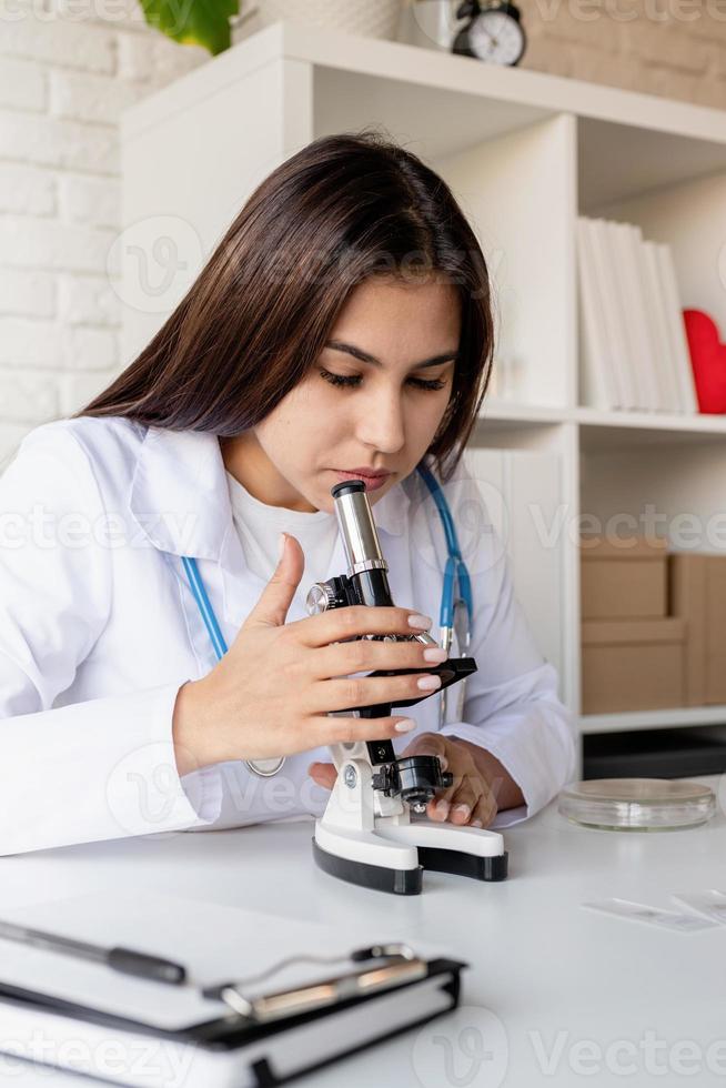 joven médico o científico mujer usando microscopio foto