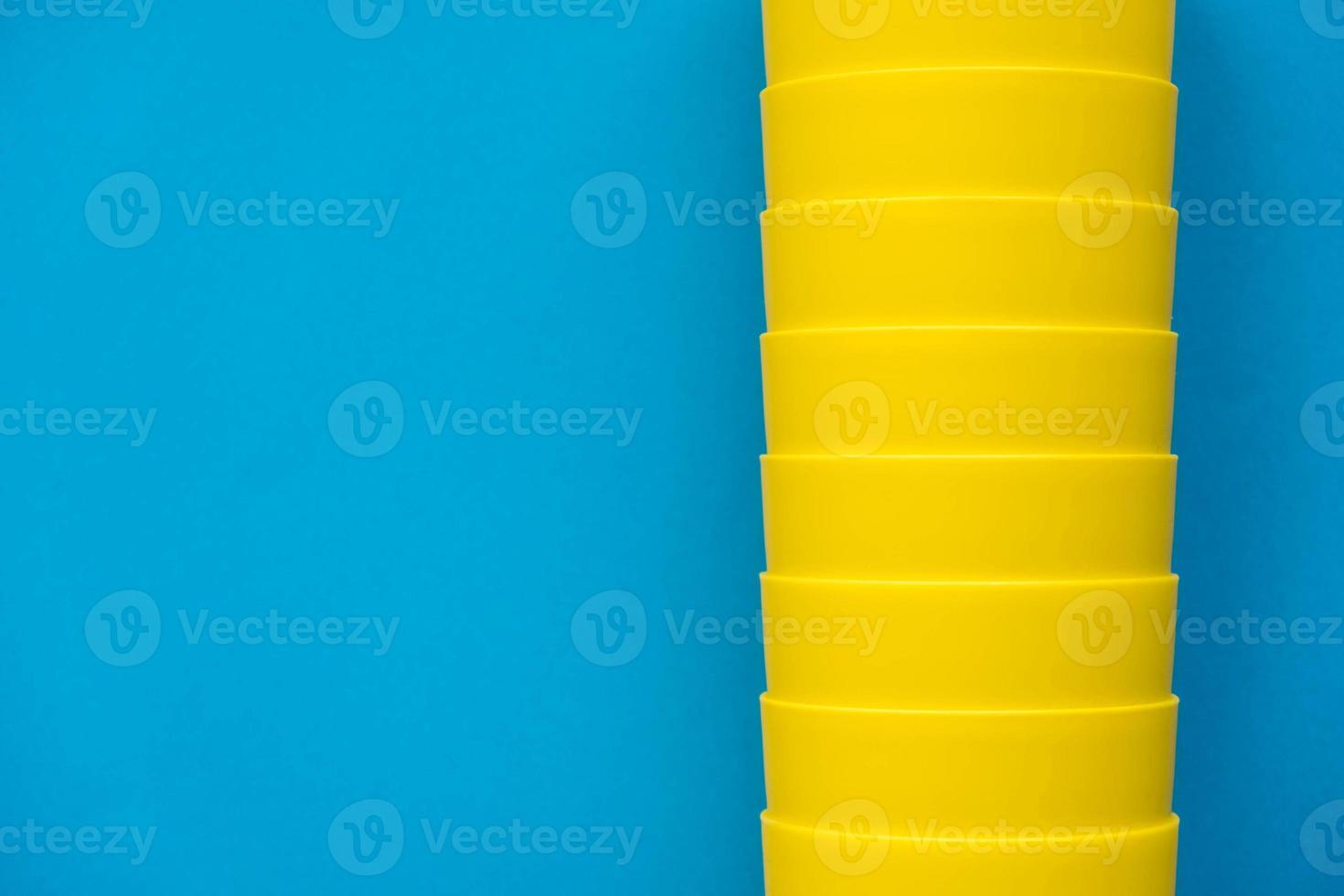 Many blue paper disposable cups on yellow background photo