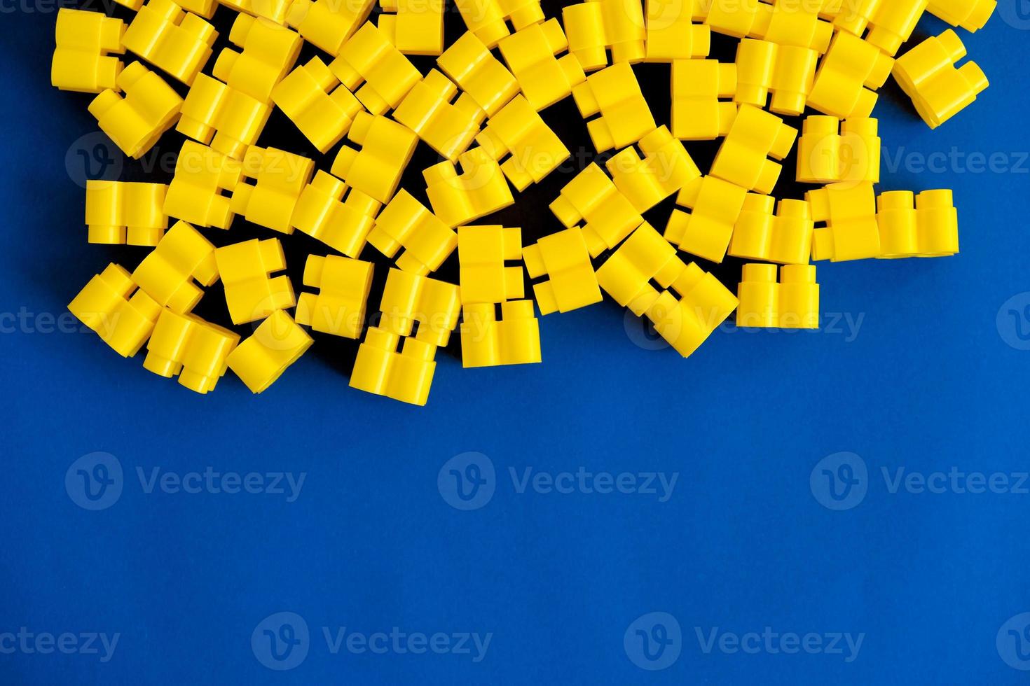 Yellow plastic building blocks on a blue background photo