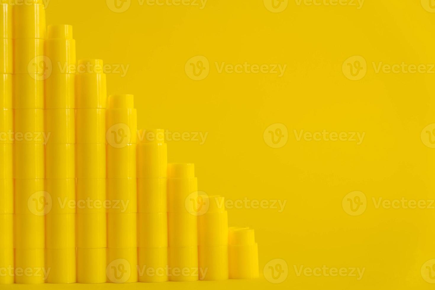 Yellow plastic building blocks in the shape of a pyramid on yellow background. Background of plastic details building blocks. Parts of bright small spare parts for toys photo