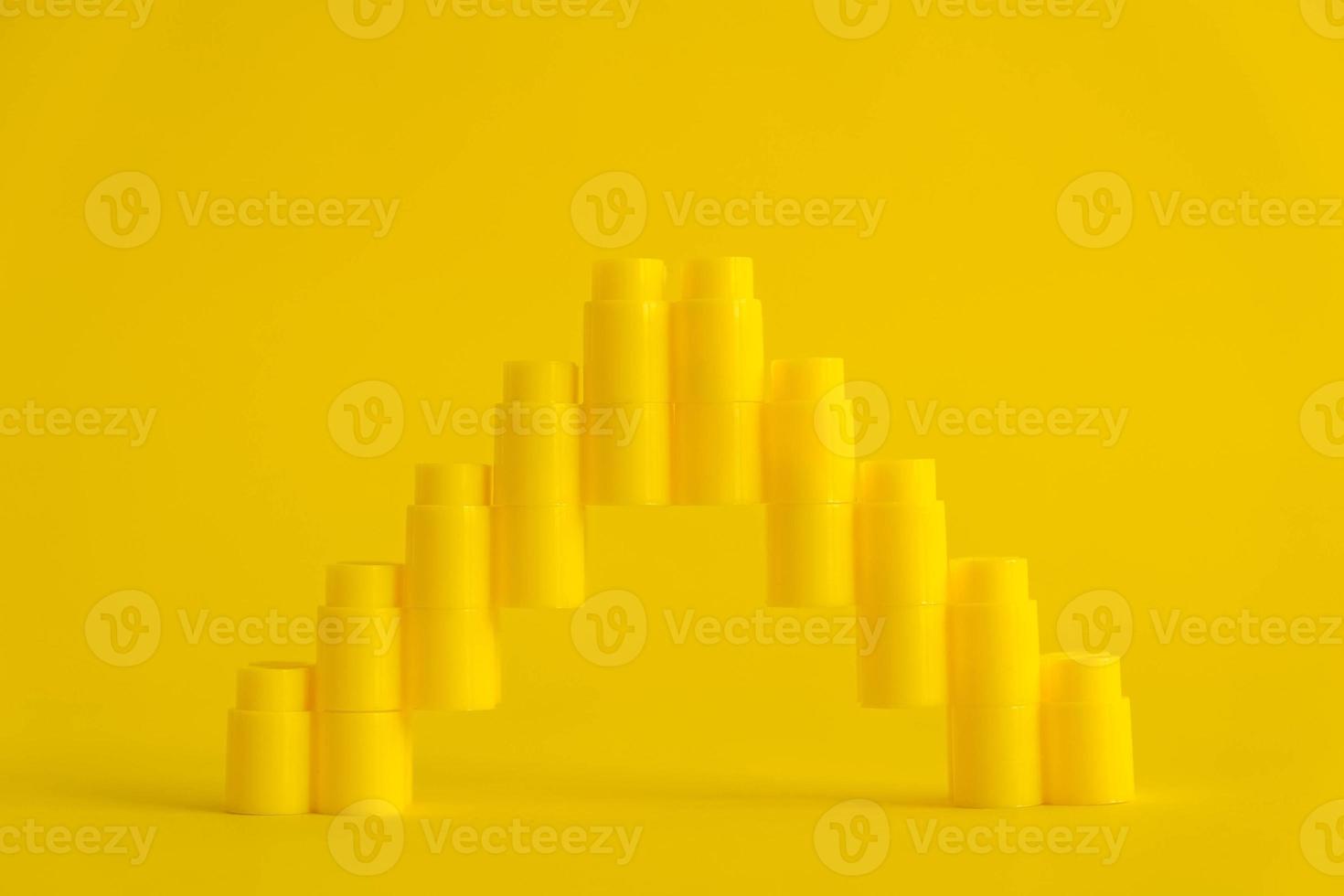 Yellow plastic building blocks in shape of a pyramid on yellow background photo