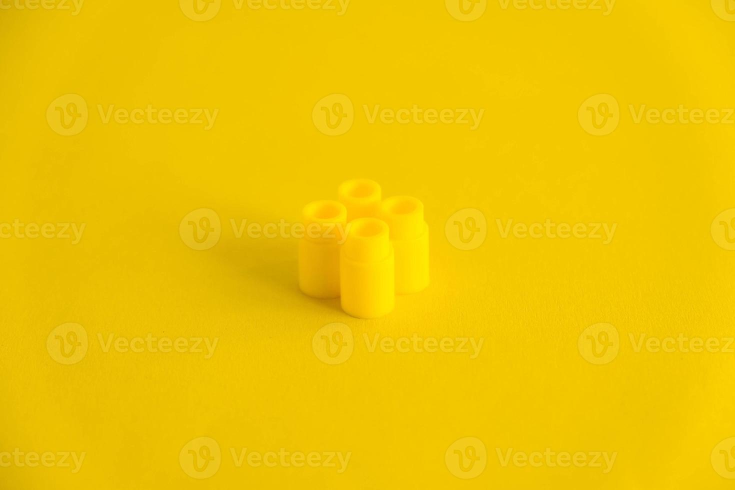 Yellow plastic building block on yellow background. Background of plastic detail building block photo