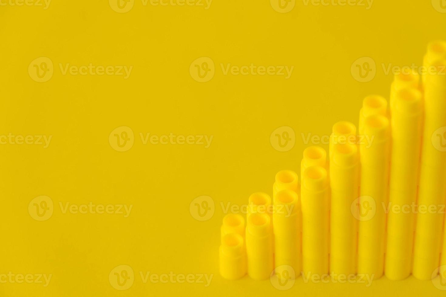 Yellow plastic building blocks in shape of a pyramid on yellow background photo