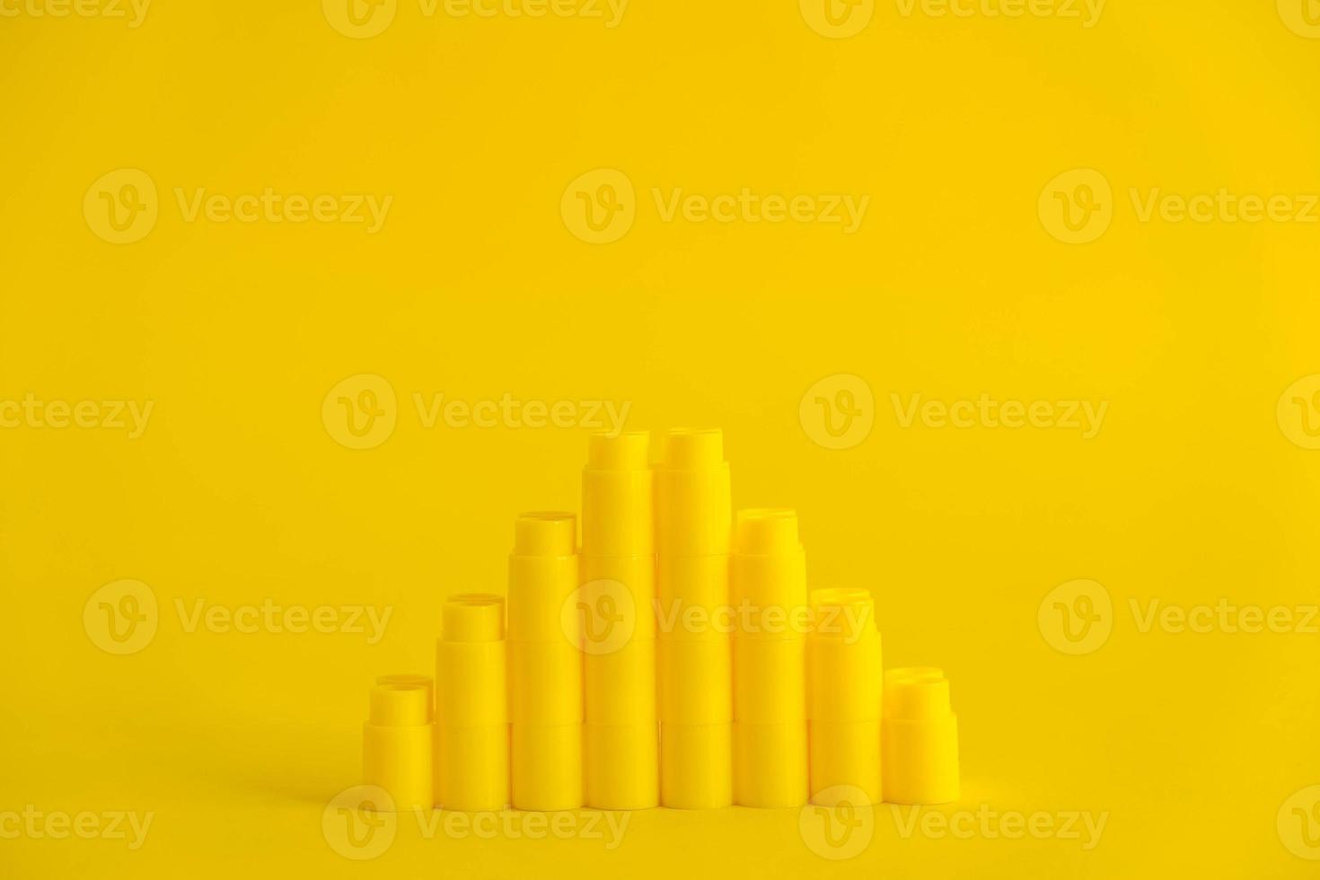 Yellow plastic building blocks in shape of a pyramid on yellow background. Background of plastic details building blocks photo