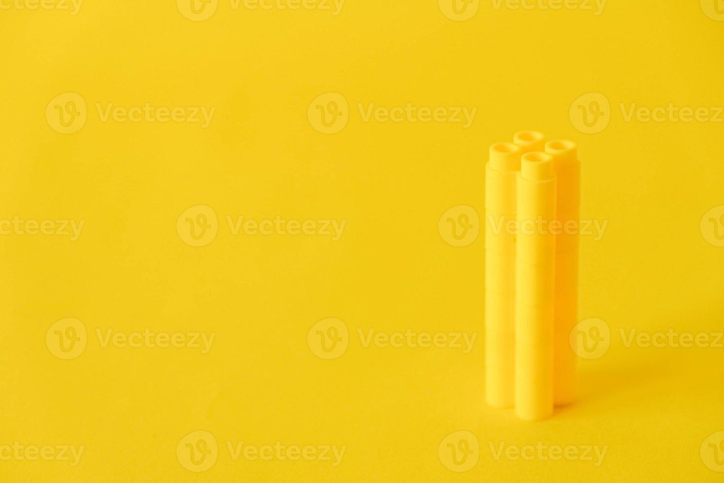 Yellow plastic building blocks in the shape of a tower on yellow background photo