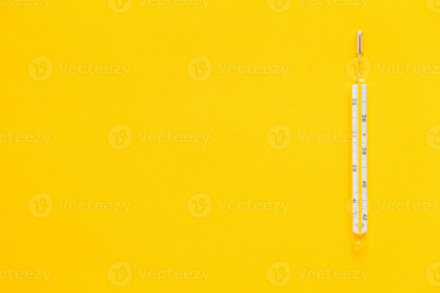 Medical mercury thermometer on a yellow background photo