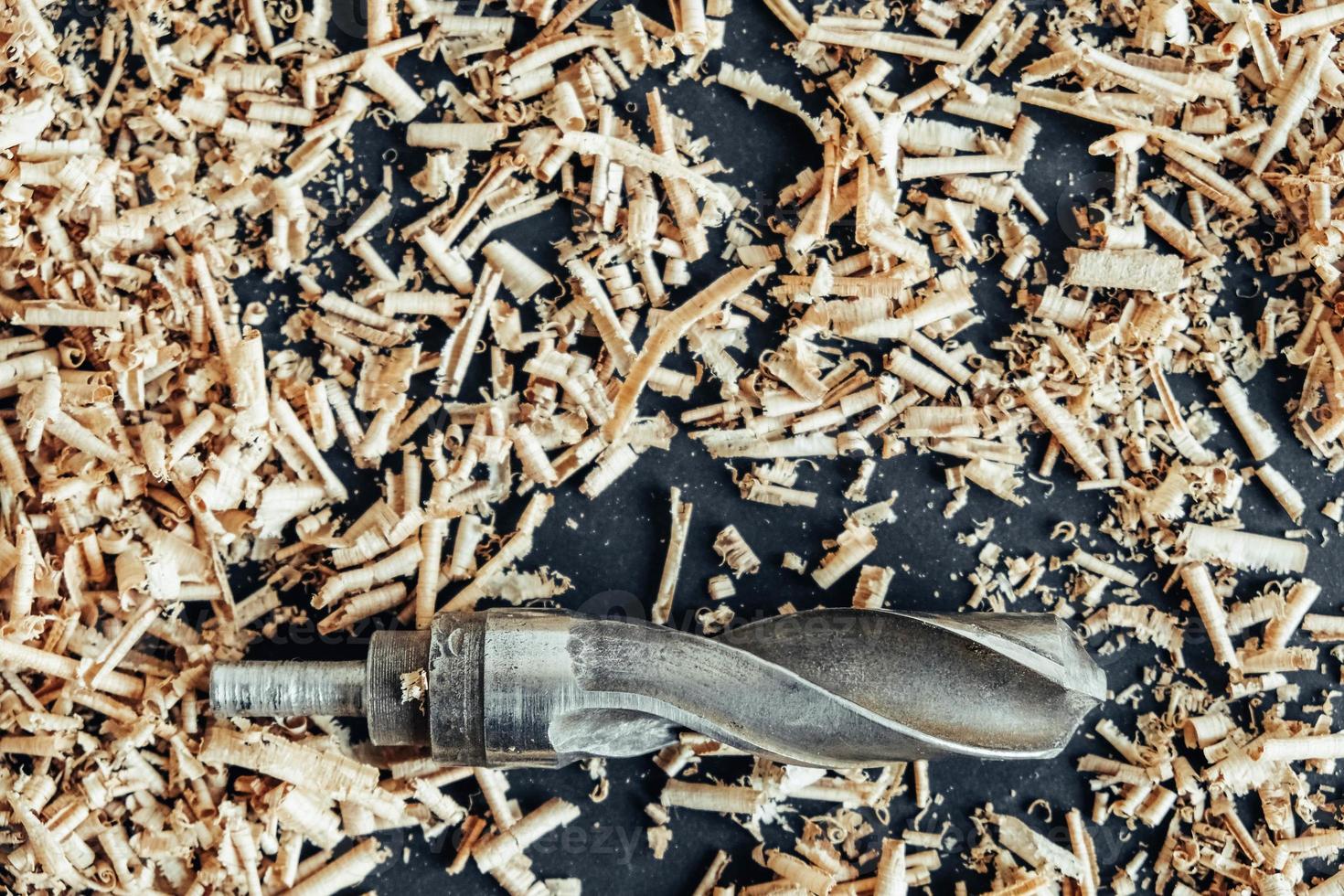 Wood drill bit with wooden shavings on black background photo