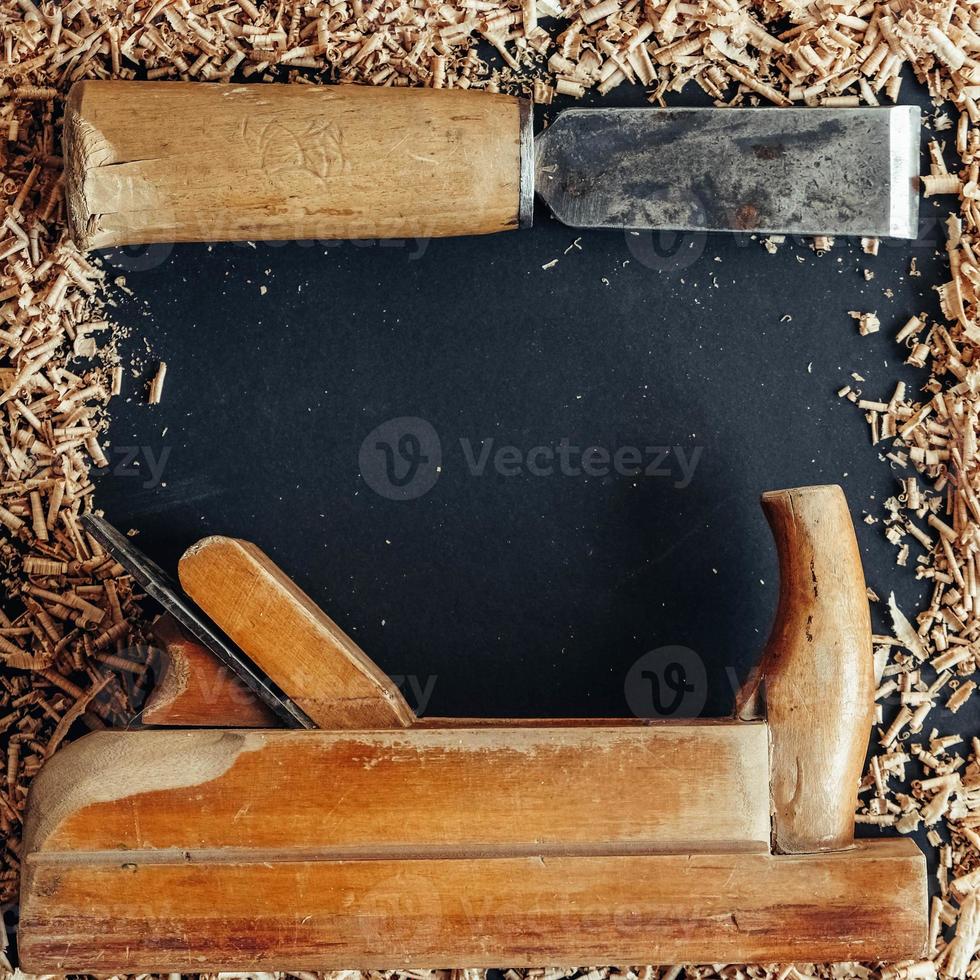 Plano de mano antiguo y cincel con virutas de madera sobre fondo negro. herramienta de mano de carpintería antigua foto
