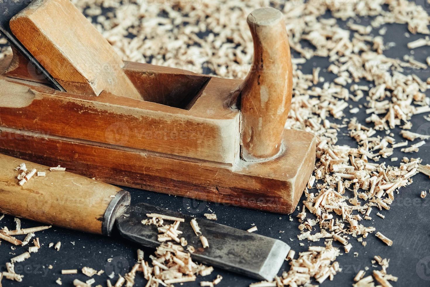 Old hand plane and chisel with wooden shavings on black background. Old woodworking hand tool. Copy, empty space for text photo