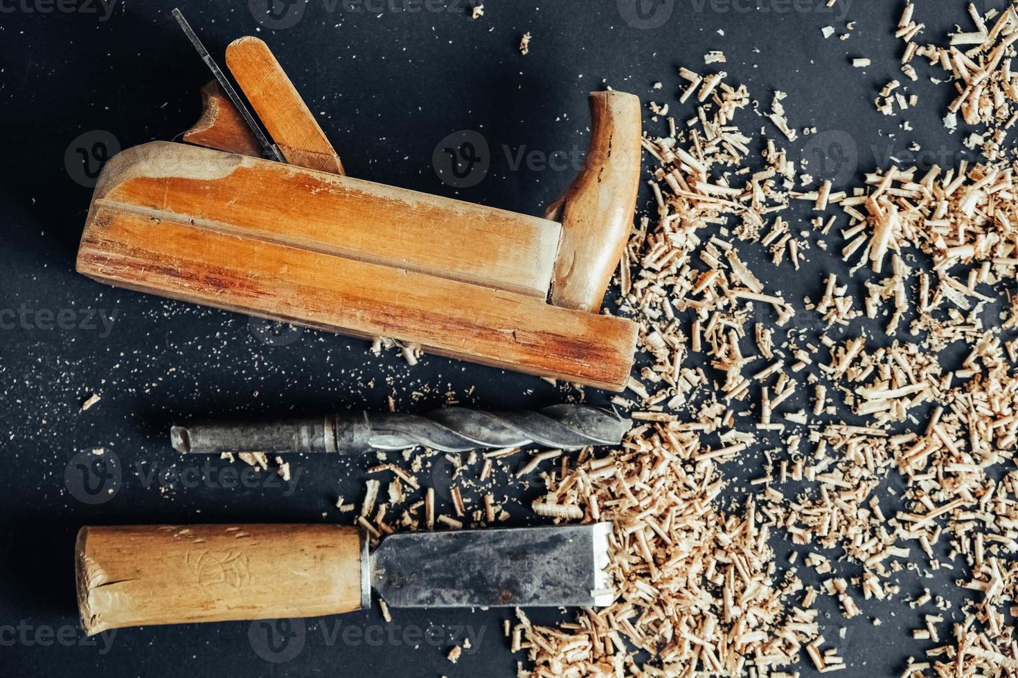 Old hand plane, drill and chisel with wooden shavings on black background. Old woodworking hand tool. Copy, empty space for text photo