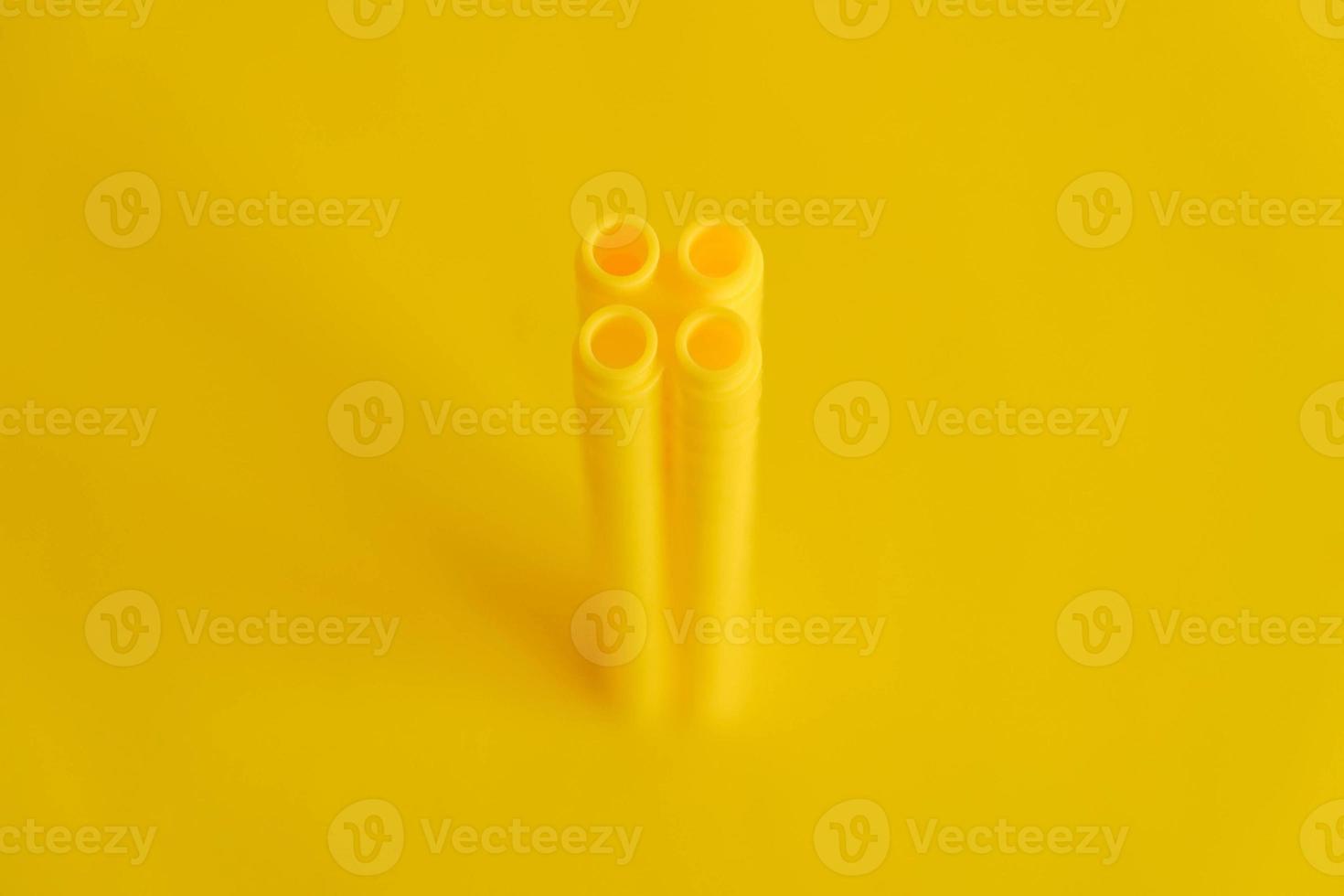 Yellow plastic building blocks in shape of a tower on yellow background. Background of plastic details building blocks photo