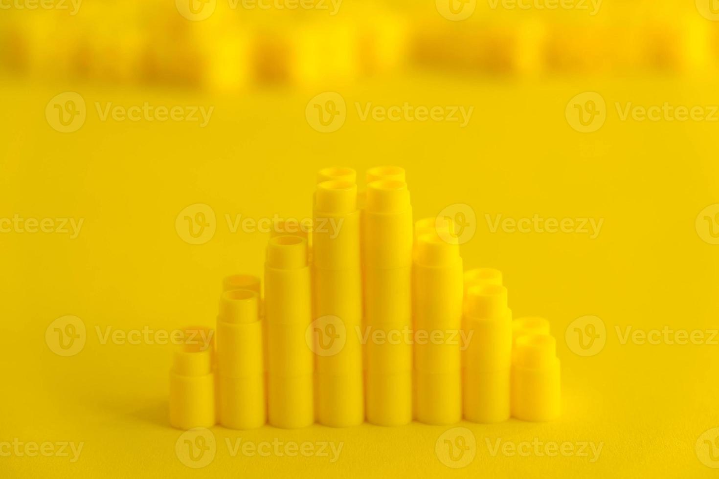 Yellow plastic building blocks in shape of a pyramid on yellow background photo