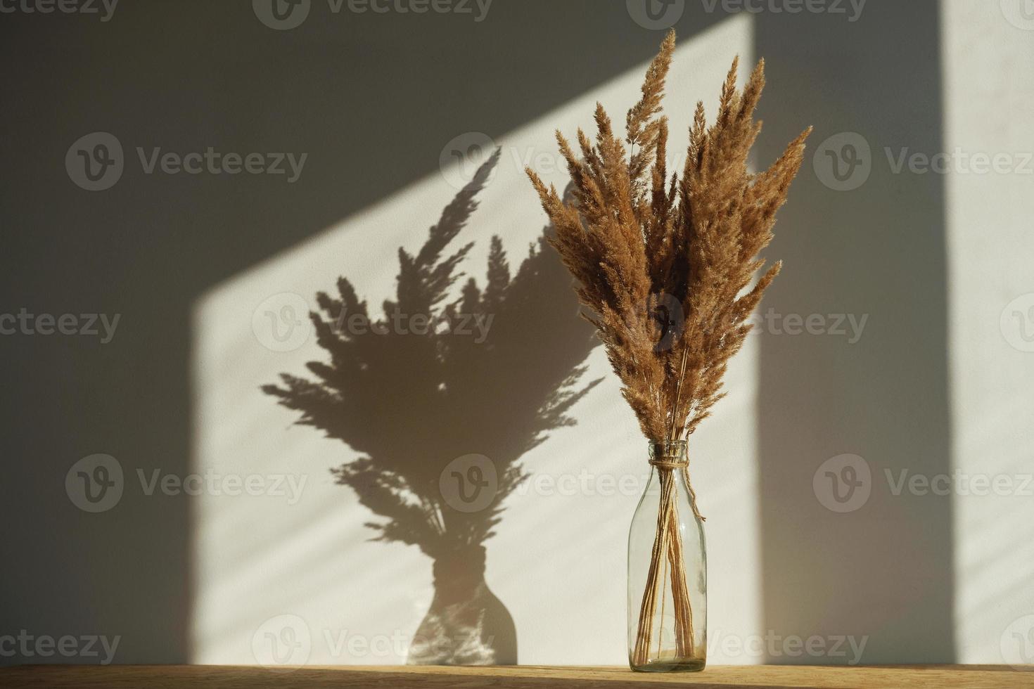 Still life of a bouquet of dried flowers in a glass bottle on a wooden table photo