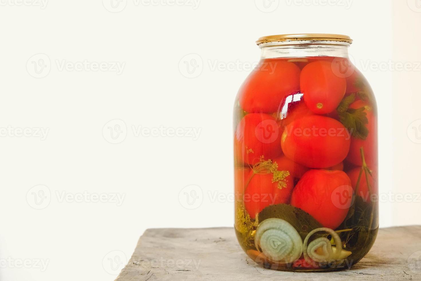 Tomate encurtido en frascos de vidrio sobre mesa de madera foto