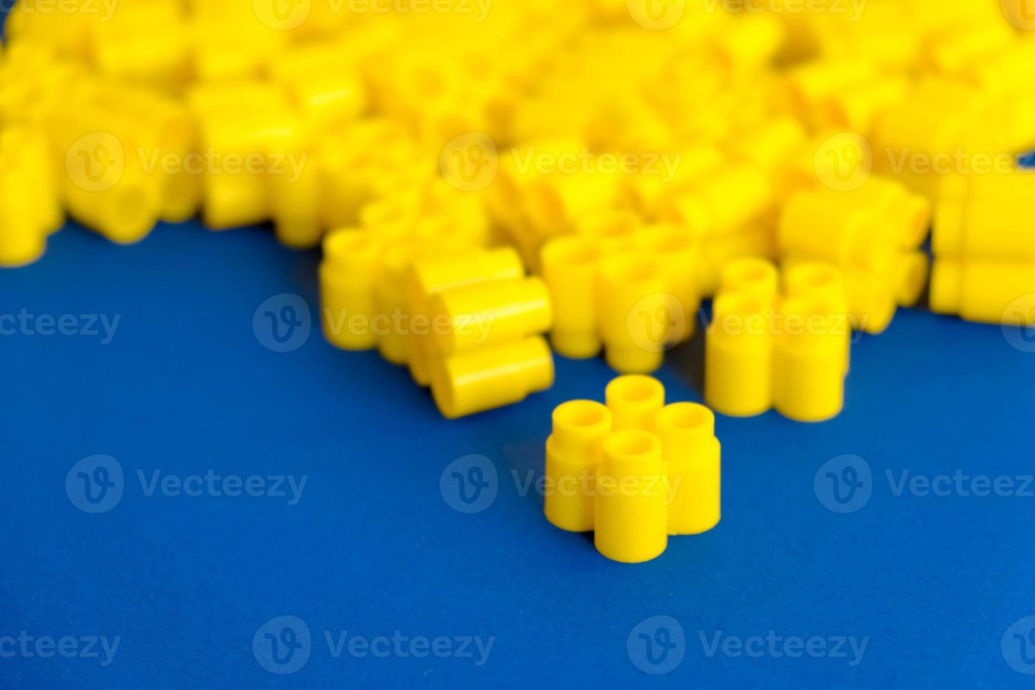 Yellow plastic building blocks on a blue background. Pieces and elements of constructor photo