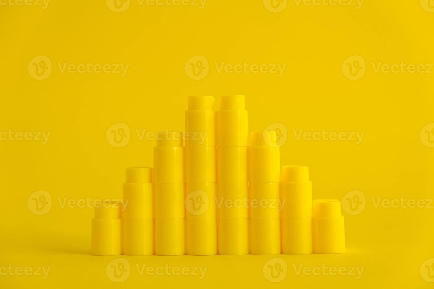 Yellow plastic building blocks in shape of a pyramid on yellow background photo