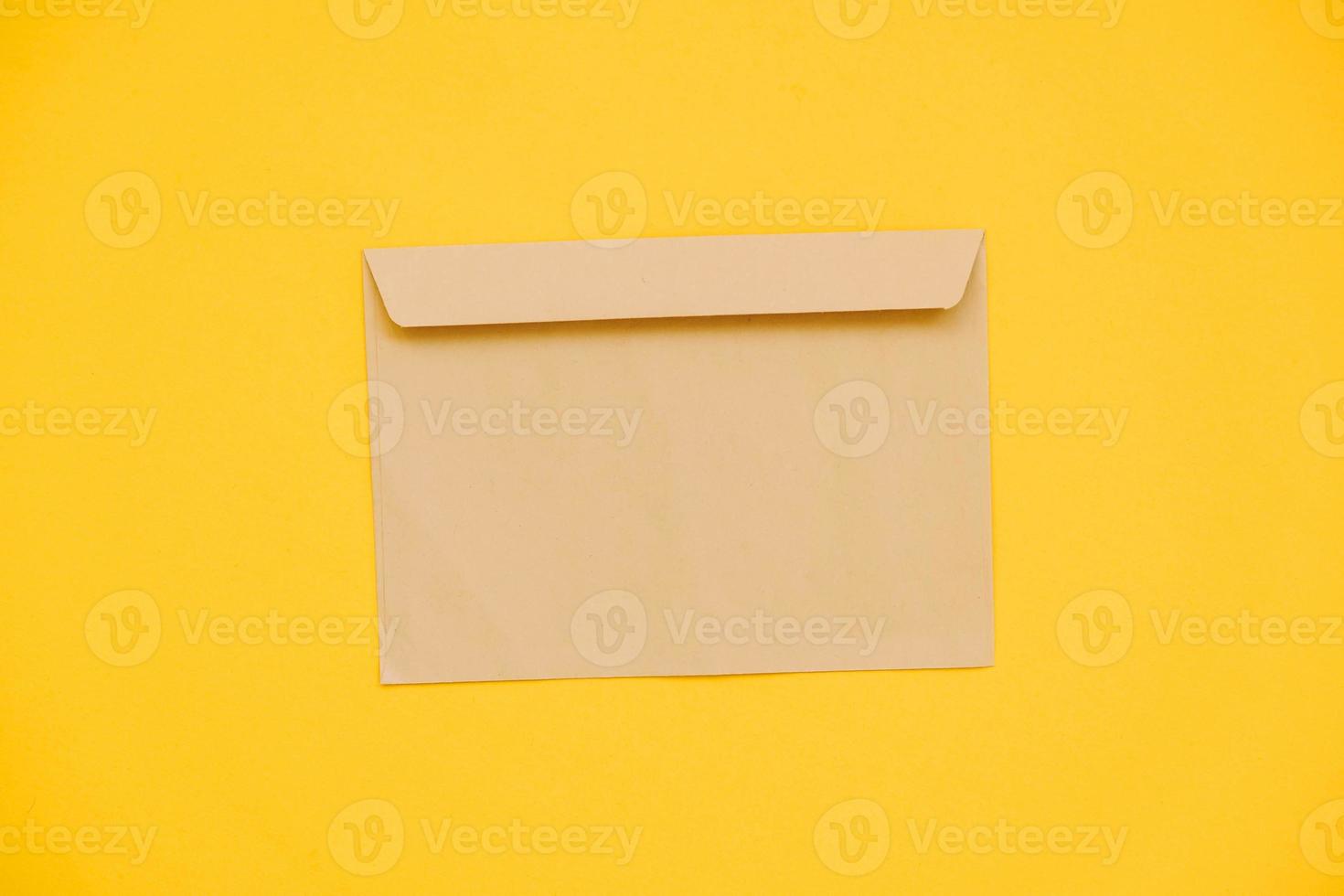 Kraft paper envelope on a yellow background. Perfect for invitations, card, message decorations photo