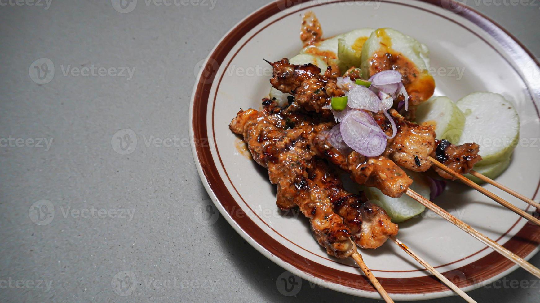 satay food complete with chili sauce and rice cake in a plate photo